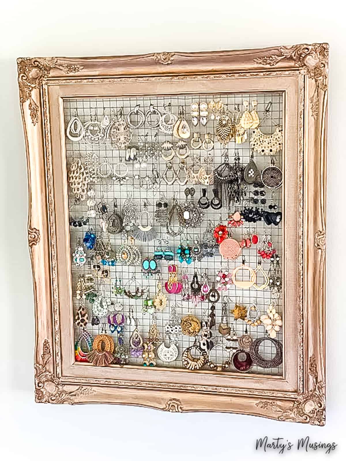 Gold frame with chicken wire and earrings organized on it
