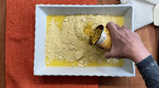 pour canned corn into mixture in white casserole dish