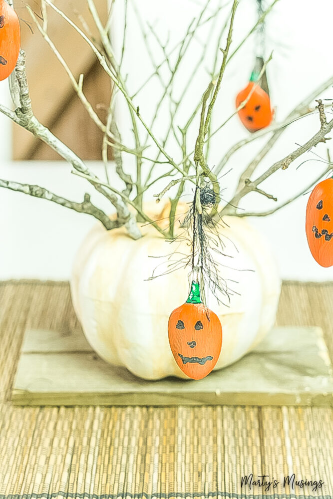 Halloween centerpiece in pumpkin with painted pumpkin spoons hanging on branches