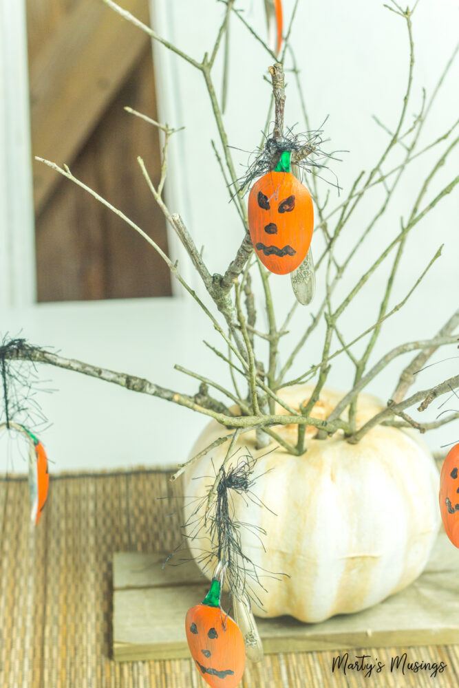 Pumpkin holding painted pumpkin spoons on branches