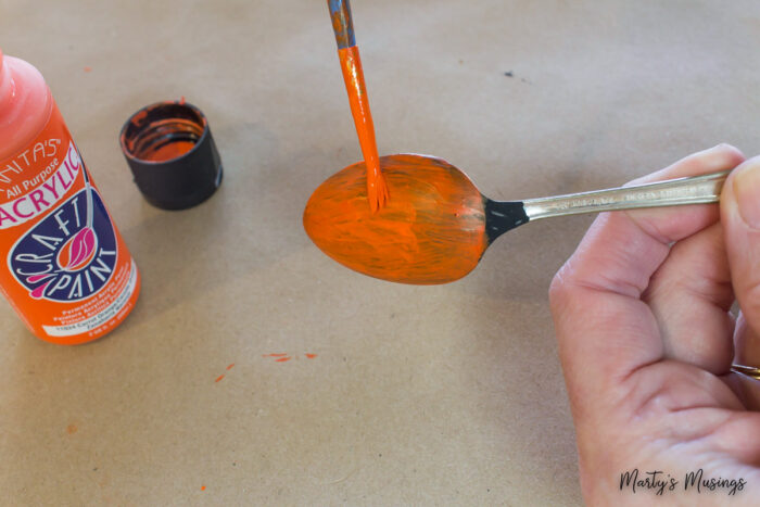 Painting spoon orange for a pumpkin
