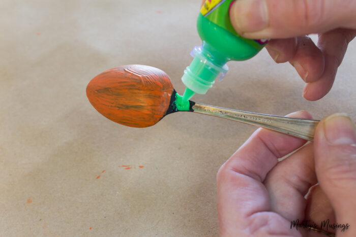 Using paint to draw pumpkin face on spoons