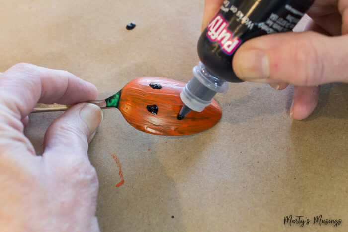 Painting pumpkin face on vintage spoons for Halloween