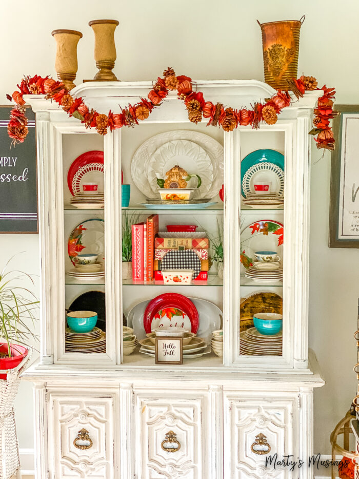 China hutch filled with orange and blue fall decorations