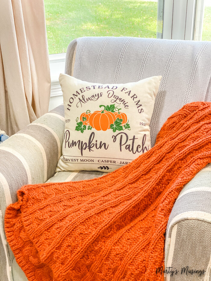 Chair with pumpkin patch pillow and orange throw