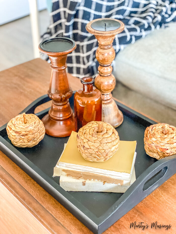 Mismatched wooden candle holders on black tray with textured pumpkins