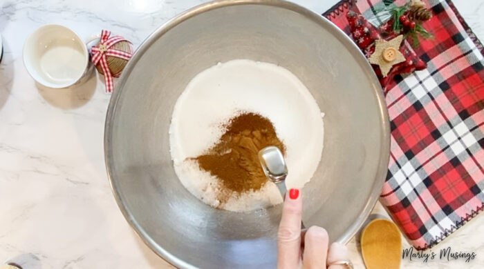 adding ground cinnamon to metal bowl mixture