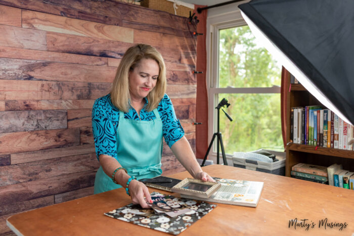 woman in blue shirt standing in front of wood wall making a project