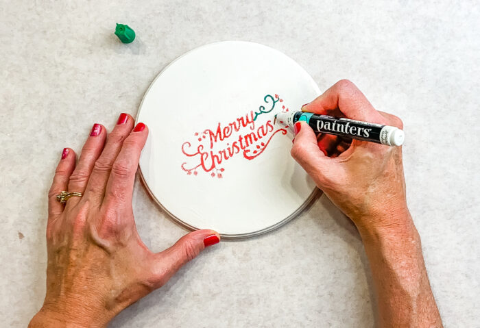 Using paint marker on white lid to write Merry Christmas