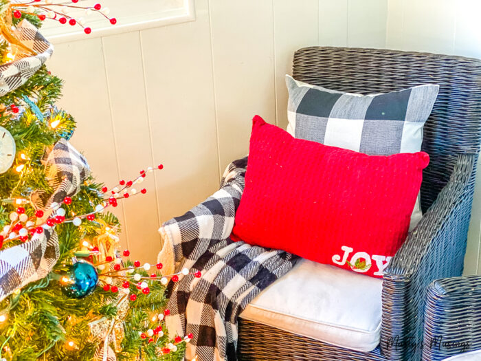Part of Christmas tree with black chair and Christmas pillows