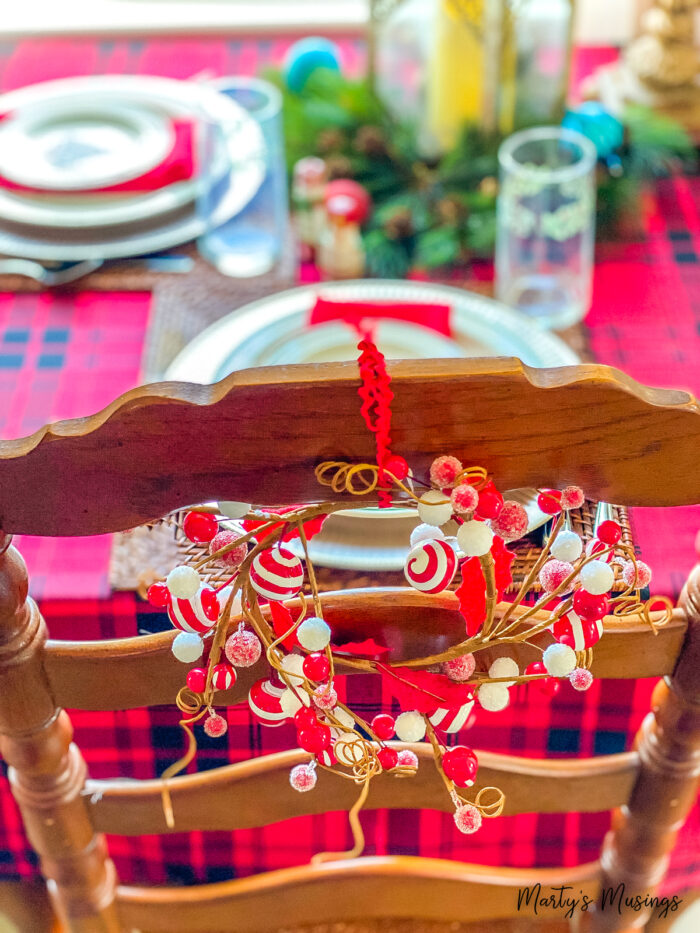 Red and white Christmas candle holder on back of wood chair