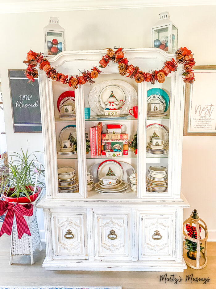 white china hutch with red and blue dishes and Christmas decorations on a budget