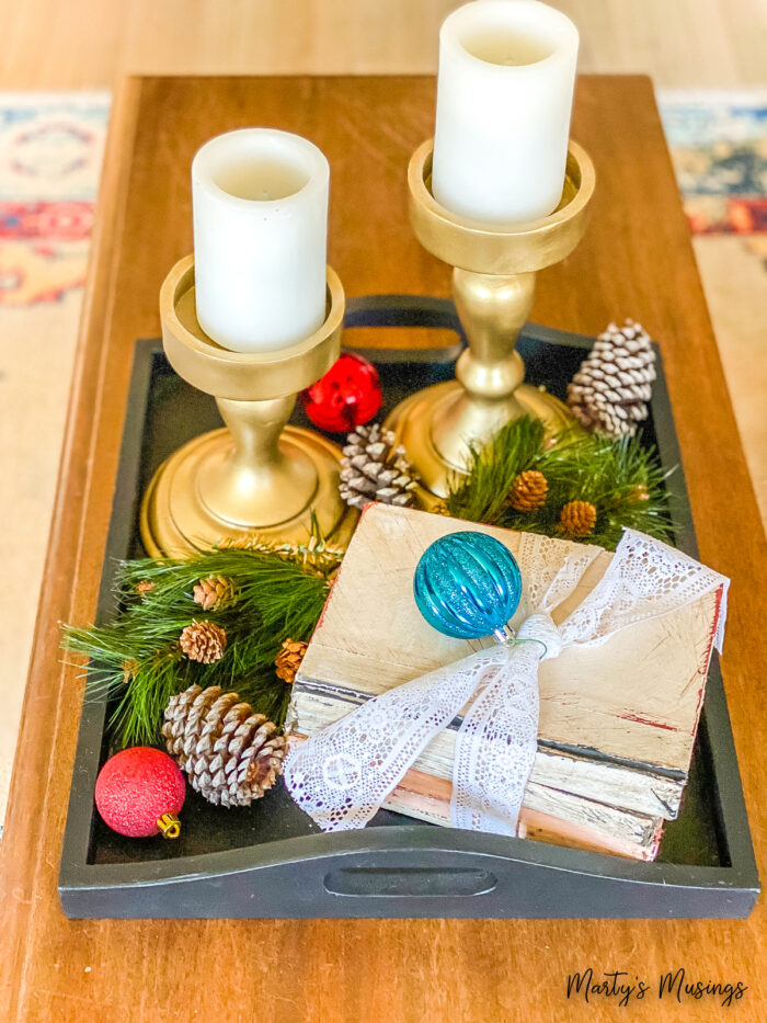 Black tray with gold candlesticks, vintage books and Christmas decor