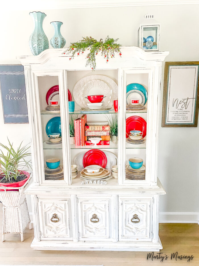 White hutch filled with blue and red dishes