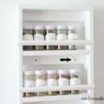 Nook in kitchen filled with spice jars with white labels and lids