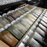Clear spice jars with labels in a kitchen drawer