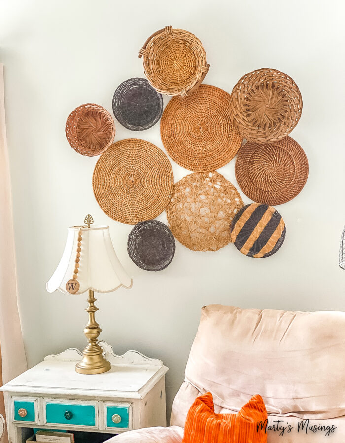 Wall display of baskets and woven mats with table and lamp