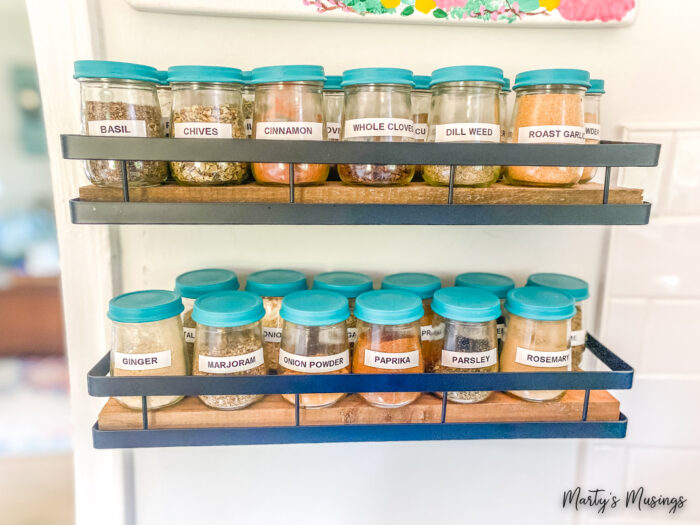 Baby food jars with blue lids and white labels hanging on wall