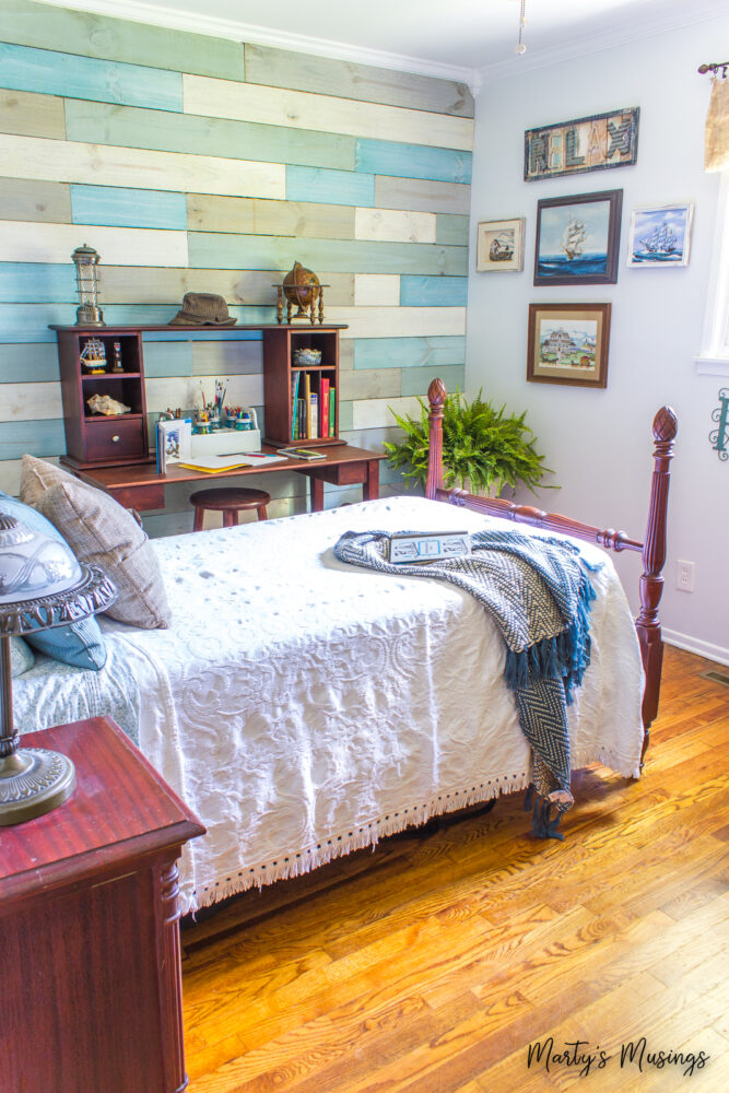 Vintage bed with white linens against coastal planked wall