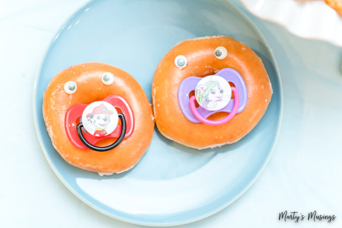 Two glazed donuts with baby pacifiers inside