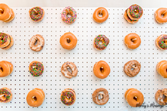 Mix of donuts hanging from pegs on white pegboard