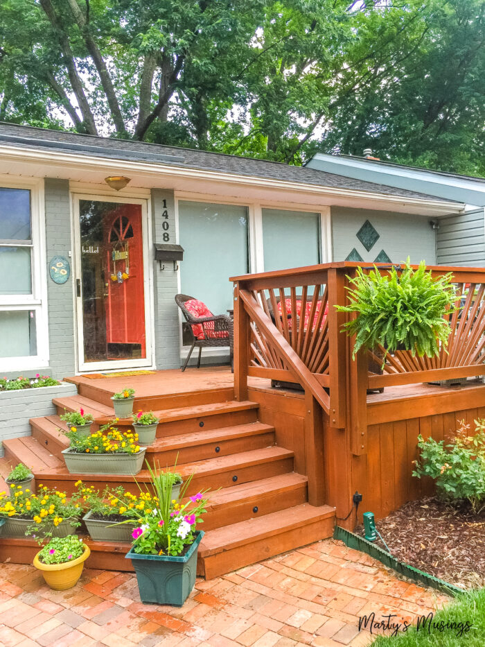 Front deck with two sides stairs and plants in middle