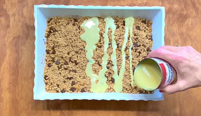 Pour sweetened condensed milk on top of chocolate bar dough