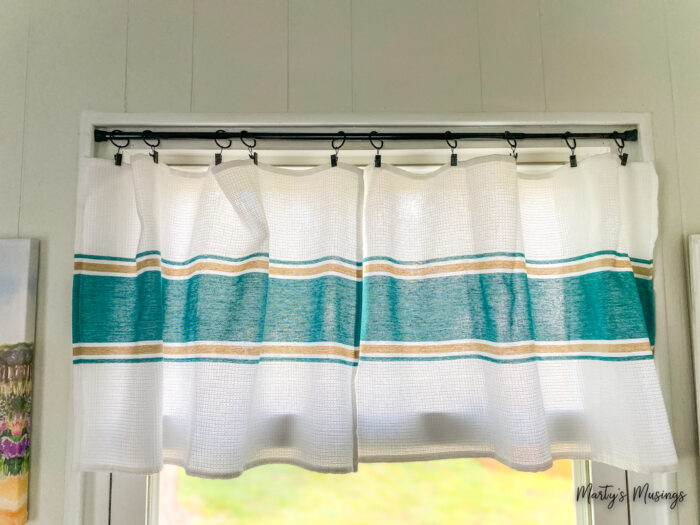 Aqua and white tea towels hung on a dowel rod with curtain clips