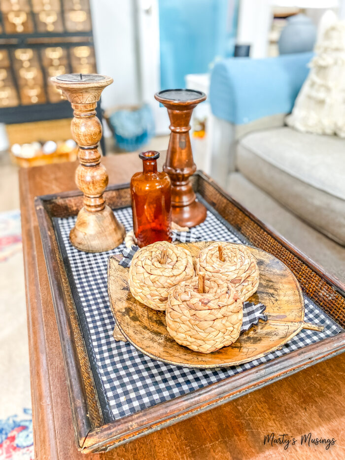 Tray with black and white buffalo plaid fabric inside and candle holders and straw pumpkins