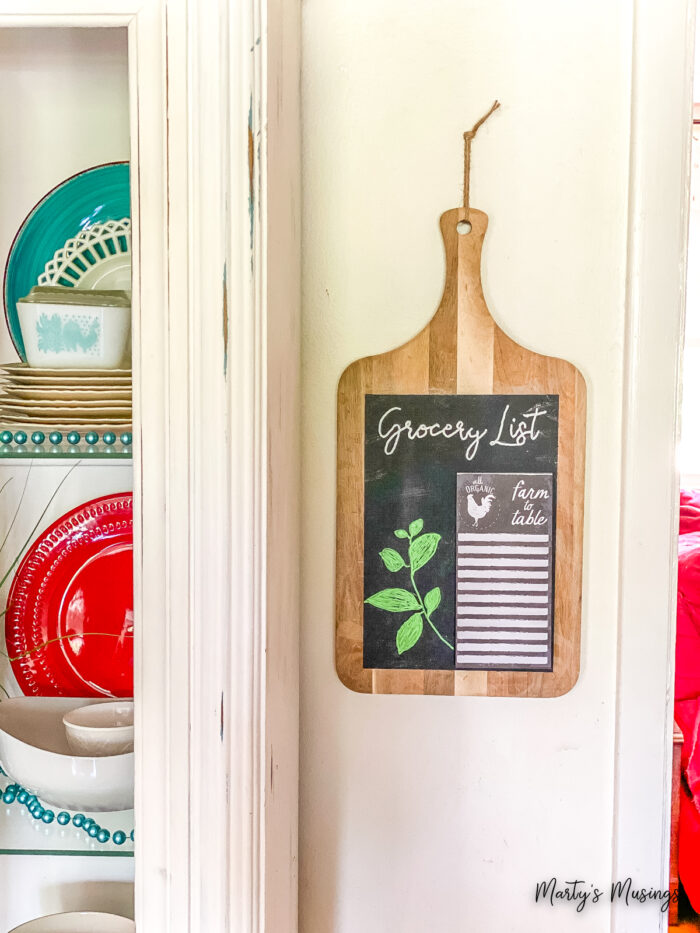 Cutting board chalkboard sign next to china hutch