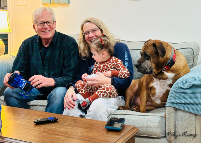 Older woman and man on couch with young girl and dog