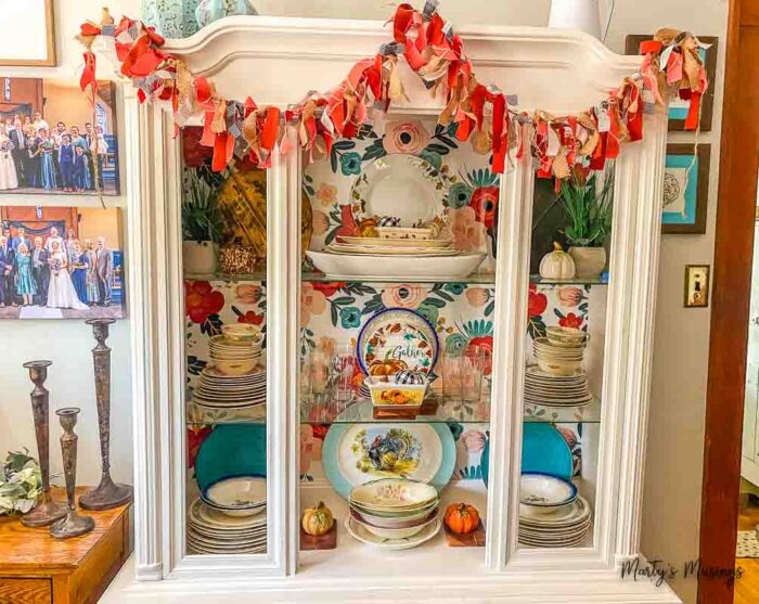 White hutch filled with fall dishes in blue and coral