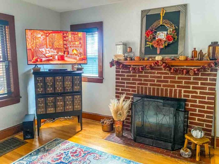 Fall screensaver on tv next to brick fireplace and mantel decorated for fall