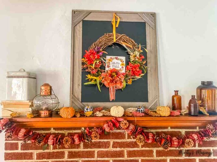 Fall mantel with black chalkboard and wreath hanging on top. Banners and vintages accessories