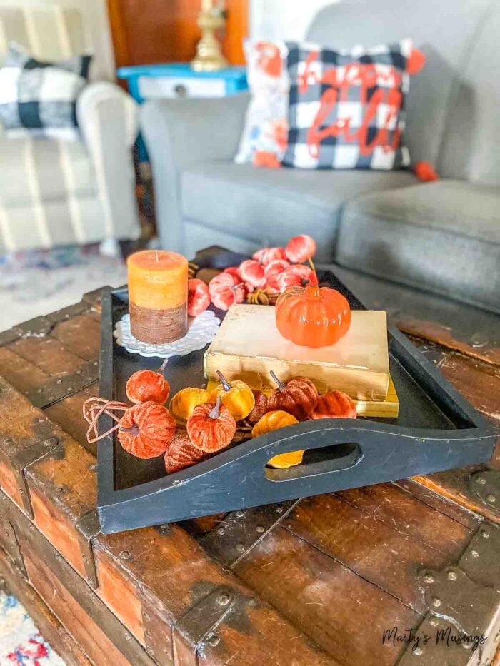Black tray filled with fall decor on top of treasure chest