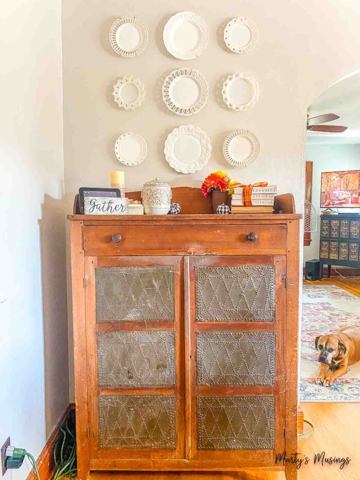 Vintage milk glass plates on wall above pie safe