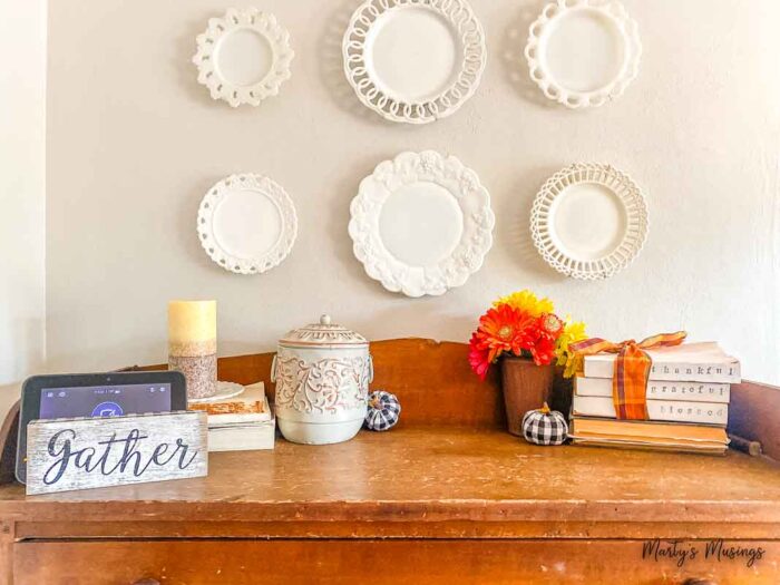 White milk glass dishes above pie safe decorated for fall
